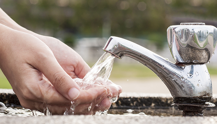 Student washes hands in public water fountain