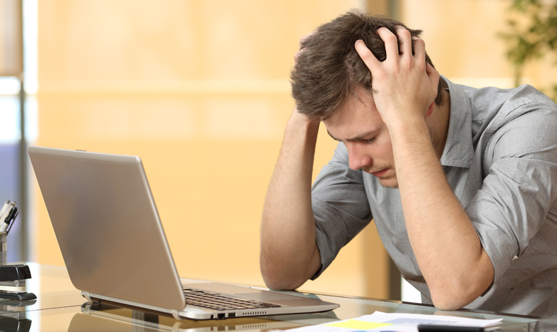 man with anxiety sits in front of laptop