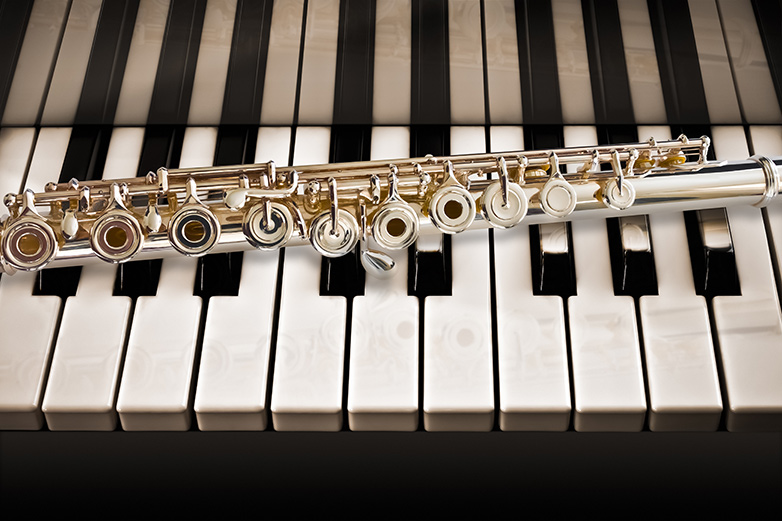 A flute lays on a piano