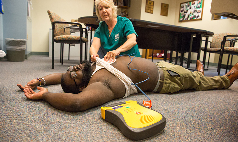 nurse using and AED defibrilator on patient