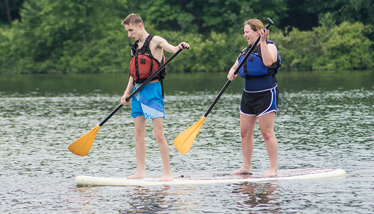 two people standing on paddle board