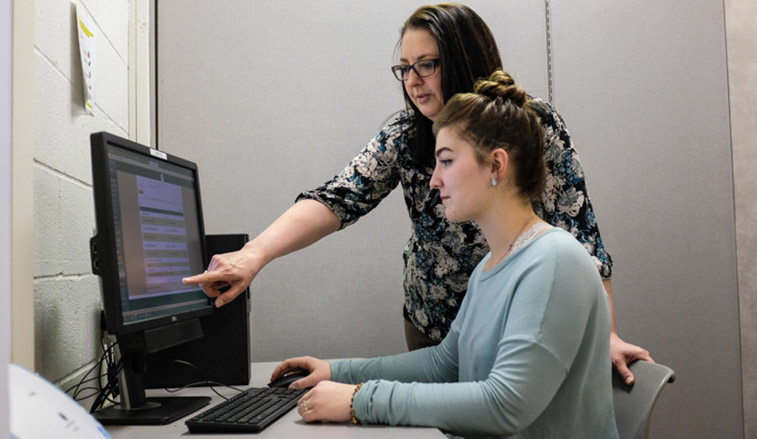Faculty memeber training a student worker on a computer