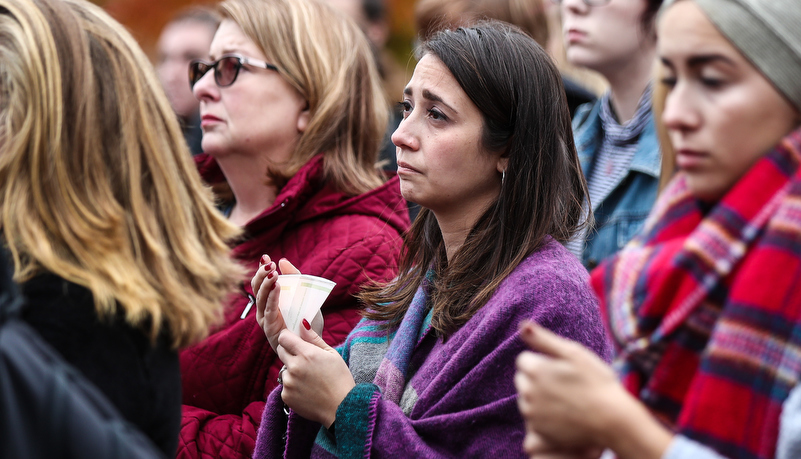 a woman listens to a speaker while holding a candle