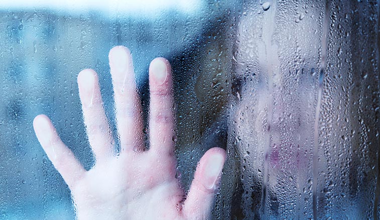 Woman looking through a rainy window
